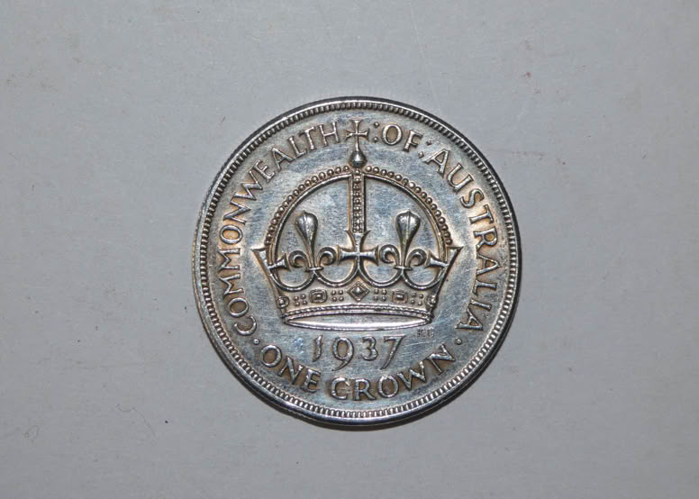 A silver coin featuring a crown design in the center, surrounded by the text "COMMONWEALTH OF AUSTRALIA" and the year "1937."