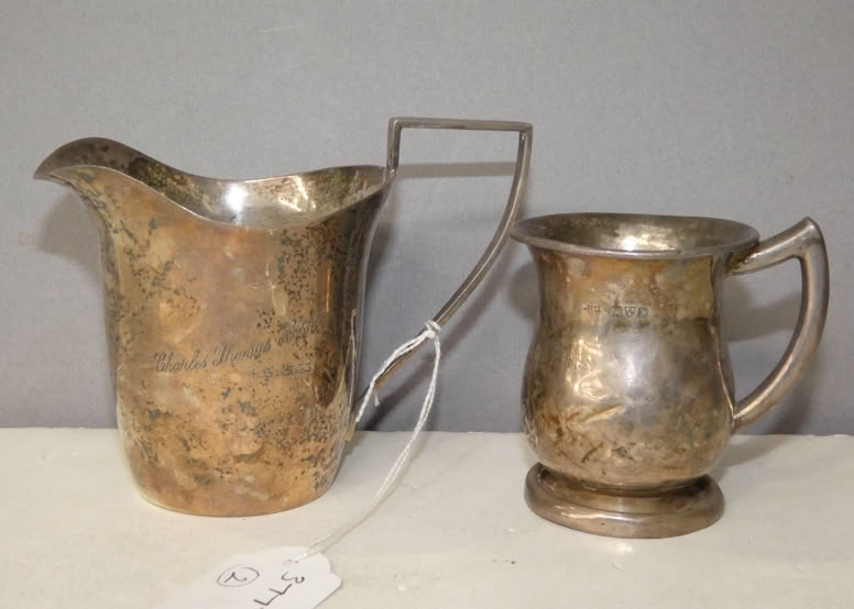 Two ornate silver pitchers with handles, one larger and one smaller, placed on a surface with a small tag labeled "40" nearby.