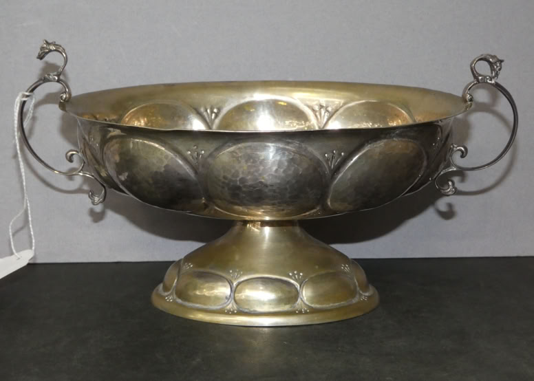 A decorative metal bowl with ornate handles and a pedestal base, featuring a pattern of raised circular designs.