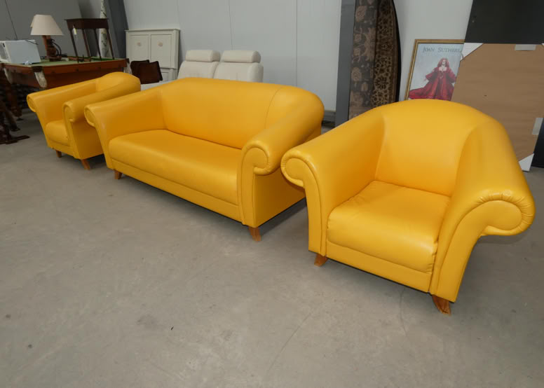 A set of yellow leather furniture including a sofa and two armchairs in a room with other miscellaneous items.
